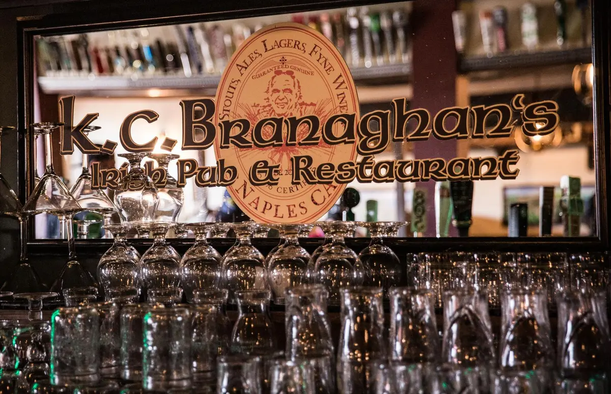 Carved wooden K.C. Branaghan's sign above the glassware at the back bar