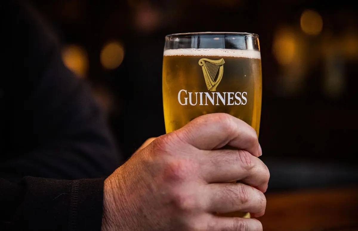A hand raising a perfectly poured pint of Guinness